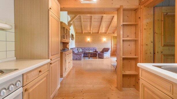 Un intérieur en bois comprenant une cuisine, un coin repas et un petit espace salon.