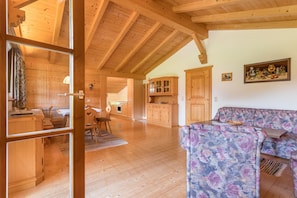 A wooden interior with a sofa, a dining table, and a kitchen area.