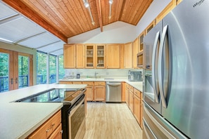 Enjoy cooking in this well-lit kitchen with a large refrigerator, cabinets, and a sink.