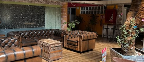 A spacious indoor area with leather sofas, a wooden table, and a decorative plant.