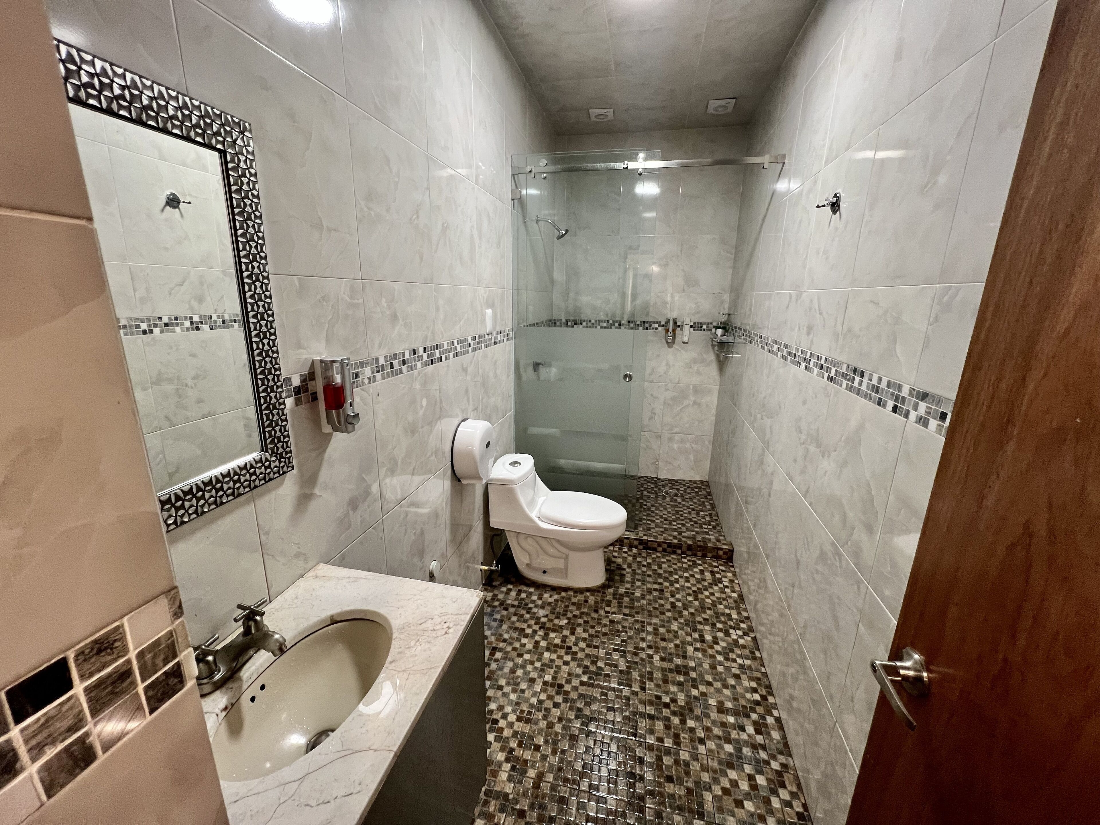 A bathroom with a marble sink, a toilet, and a glass-enclosed shower.