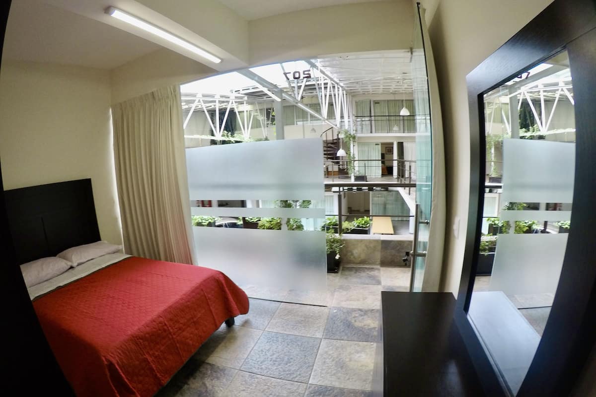 Une chambre d’hôtel avec un lit, une grande fenêtre et une vue sur l’intérieur du bâtiment.