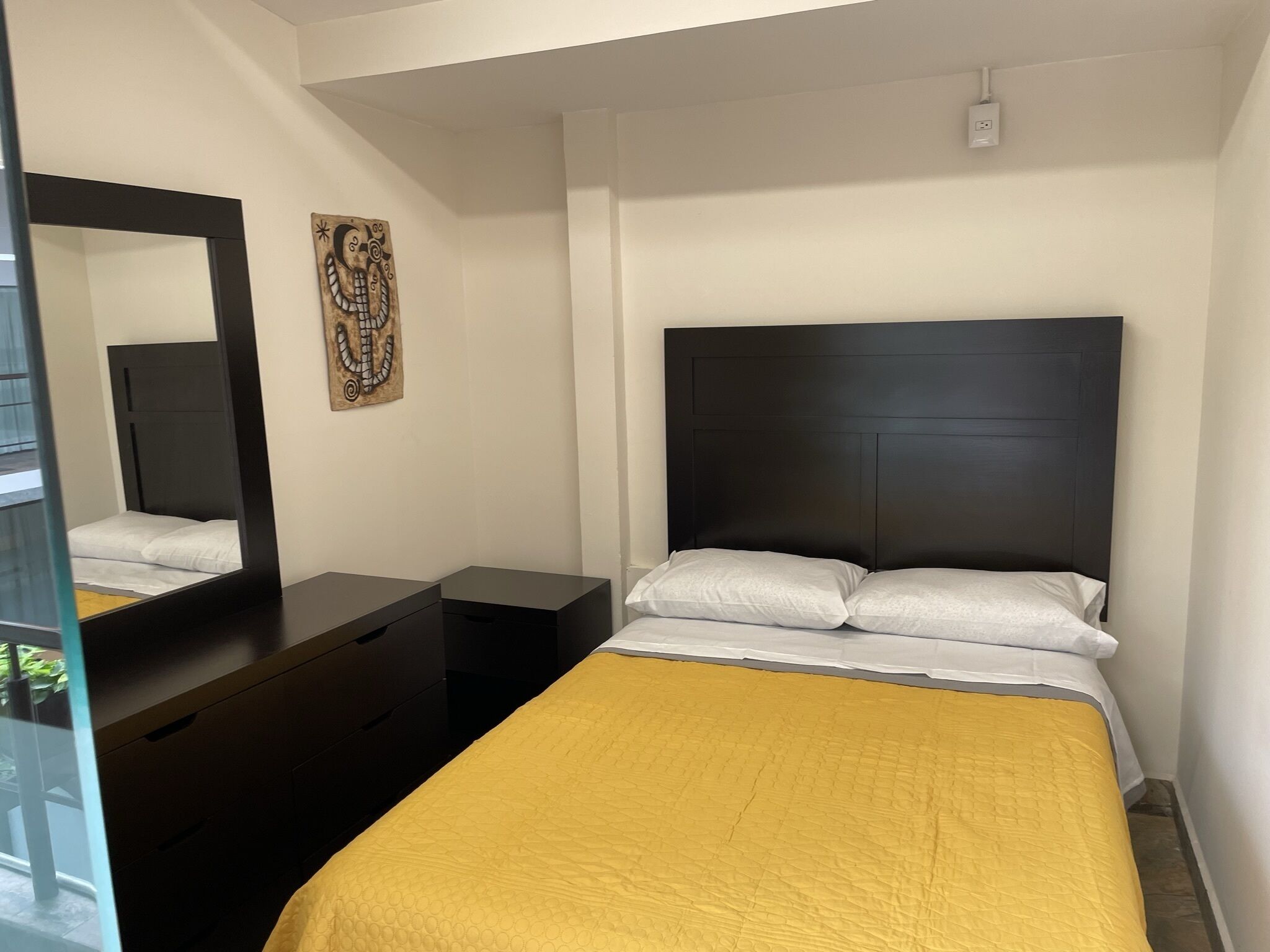 Ein Schlafzimmer mit einem Bett, einem Schminktisch, einem Spiegel und einem Wandbild.