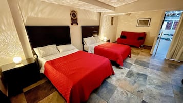 Una habitación de hotel con dos camas, una mesita de noche, una silla roja y una pequeña mesa.