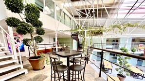 A spacious indoor area with a dining table and chairs, surrounded by potted plants and a staircase. - Downtown Treasure Place (Mexico City)