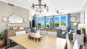 Un salon moderne avec un coin repas, de grandes fenêtres et une vue sur l’extérieur.