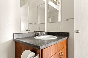 Bathroom features a granite countertop, white sink, and wooden cabinet.