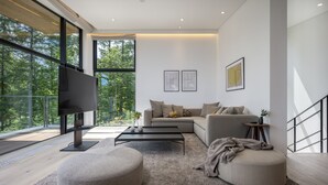 A modern living room with a large flat-screen TV, a sofa, a coffee table, and a view of the outdoors. - Ryoun by H2 Life (Kutchan)
