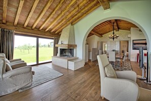 Cozy living area with a fireplace, sofas, and a dining table, offering a seamless transition to the outdoor space.