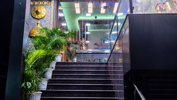 Una escalera conduce a una recepción con una pared verde, un reloj y un letrero que indica los baños.