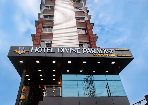 The exterior of Hotel Divine Paradise, a luxury stay building with a prominent sign and a modern design.