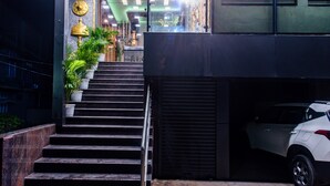 Un conjunto de escaleras exteriores que conducen a la entrada de un edificio, con un coche aparcado cerca.