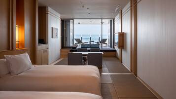A hotel room with a large bed, a desk, and a view of the sea.