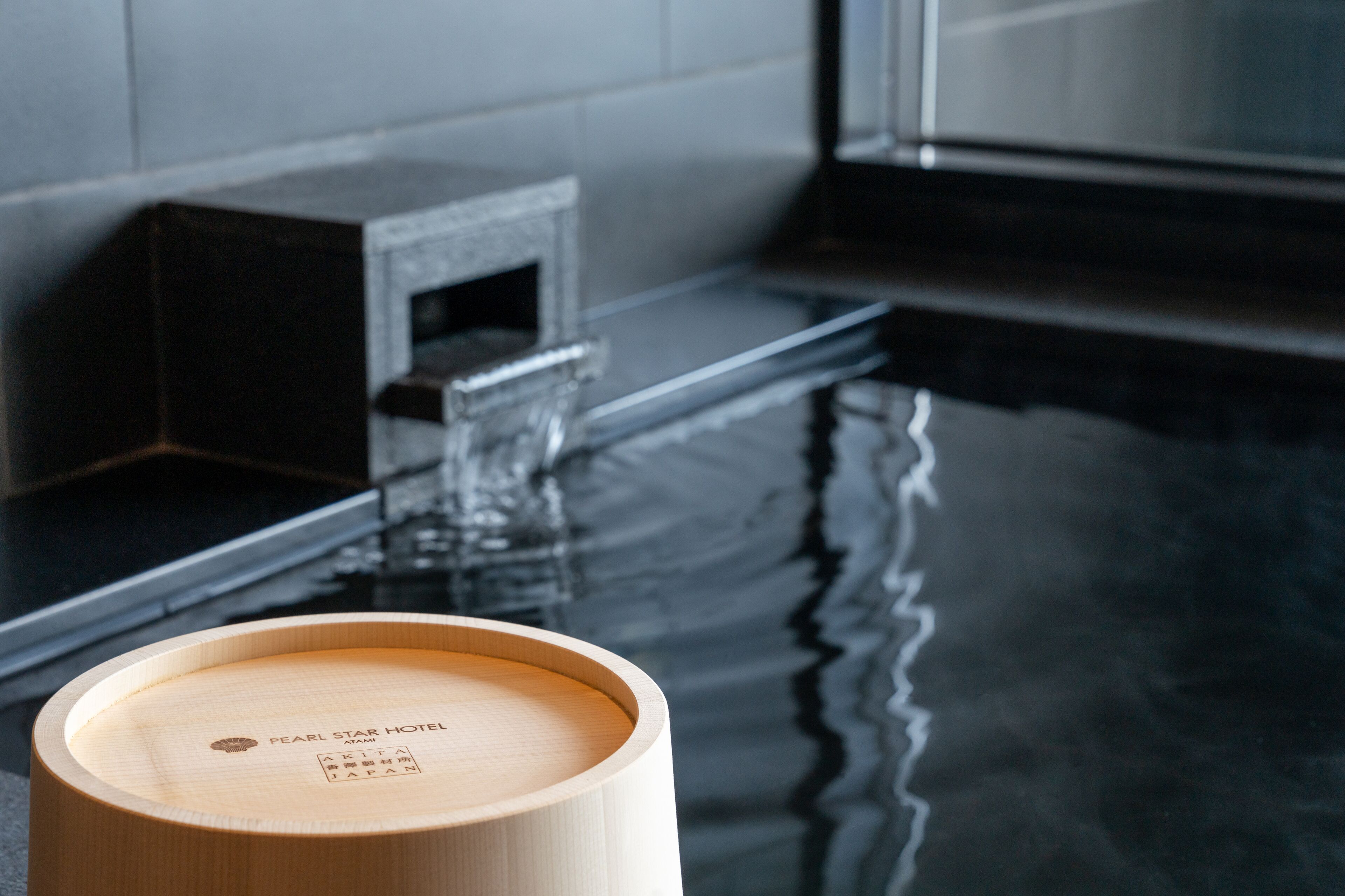 A wooden container with text on it, placed on a reflective surface, likely a table or counter.