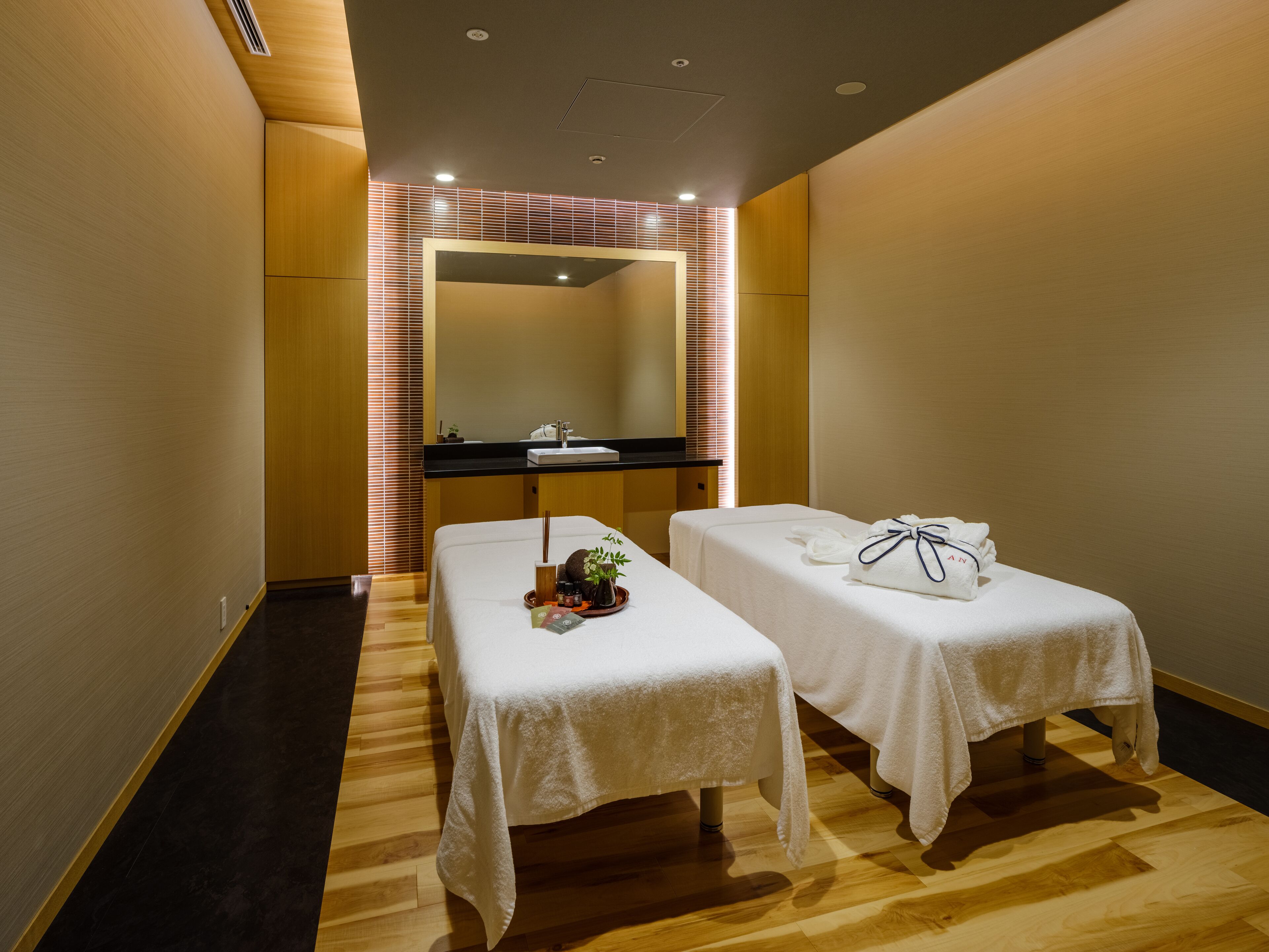 A hotel room with two beds, a bathroom with a sink, and a mirror.