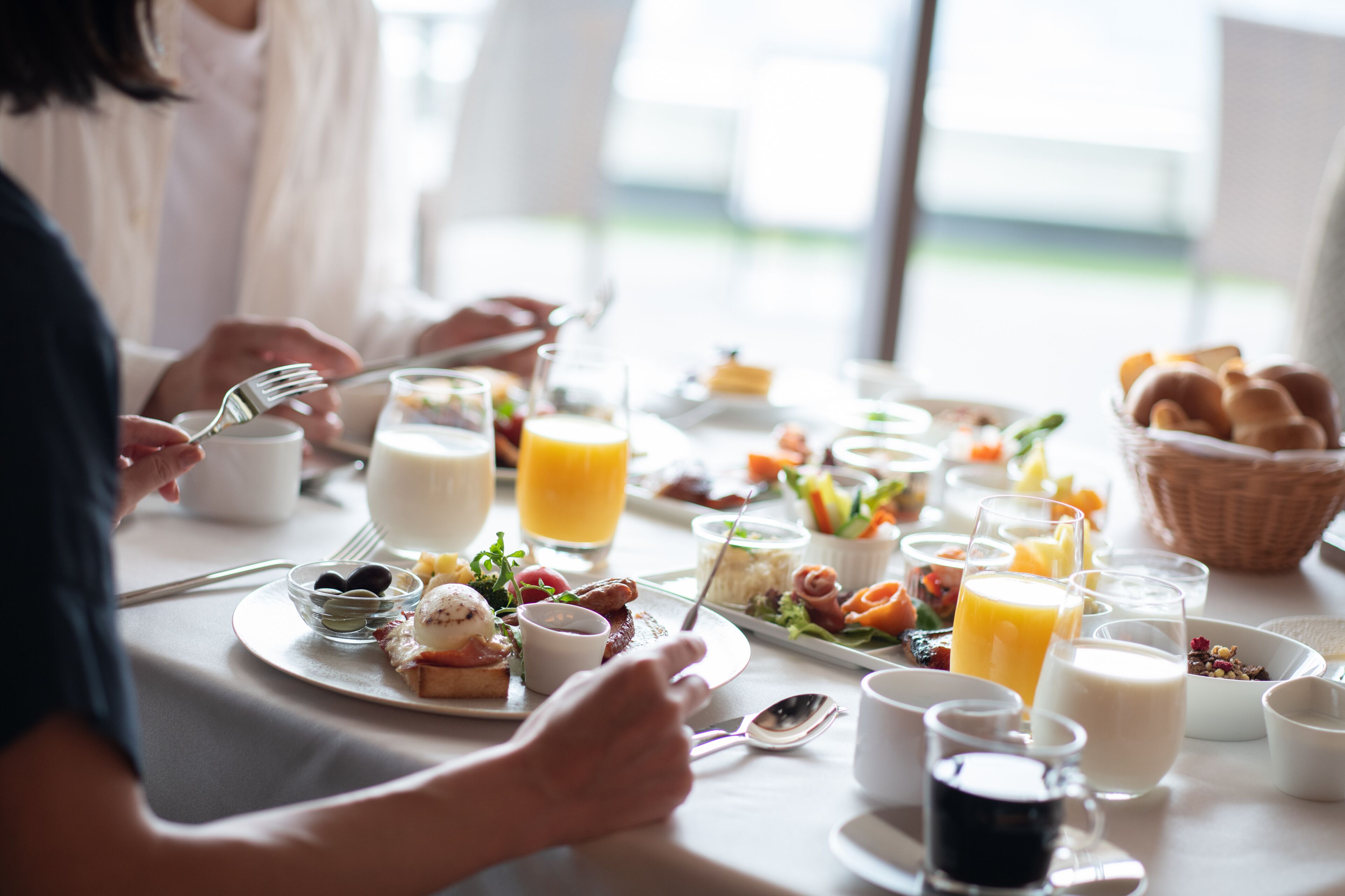 A breakfast setting with various dishes, drinks, and utensils on a table.