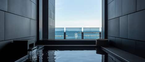 Een aparte badkuip en douche, een bronwaterbad, een regendouche