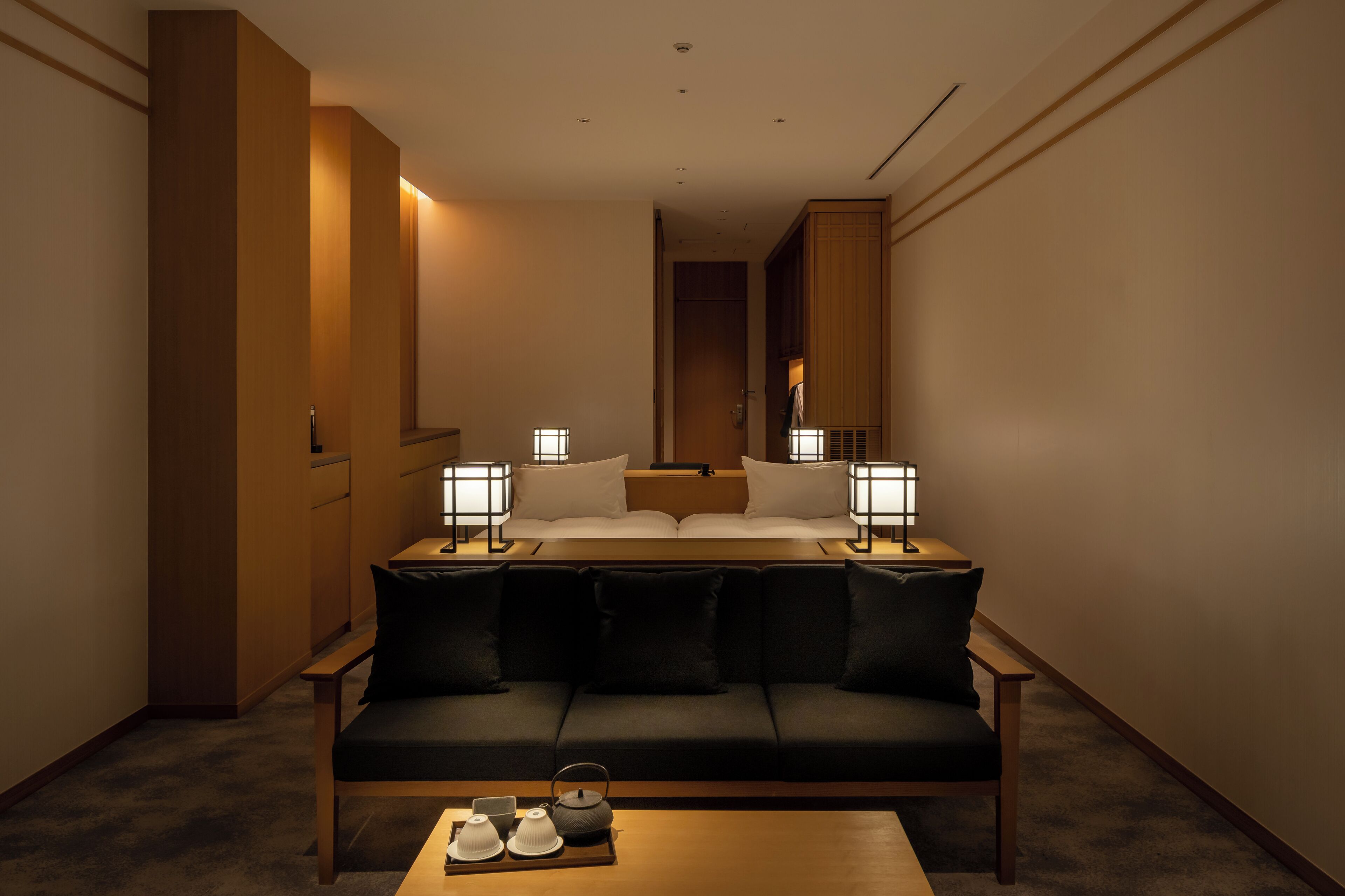 A hotel room with a bed, a sofa, a coffee table, and bedside lamps.