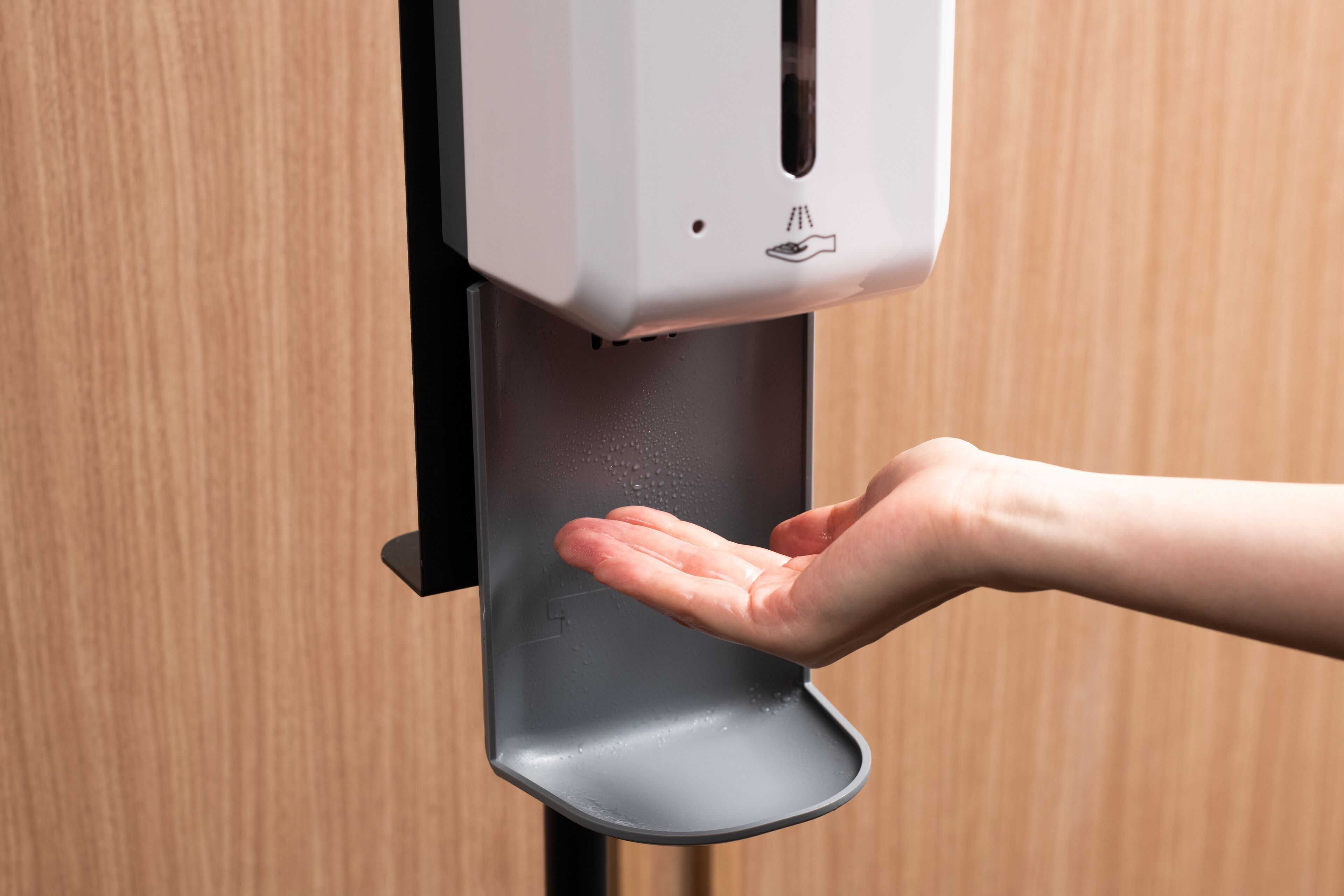 A hand dispensing soap from a dispenser mounted on a wall.
