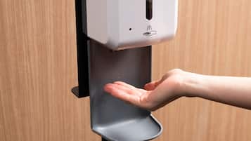 A hand dispensing soap from a dispenser mounted on a wall.