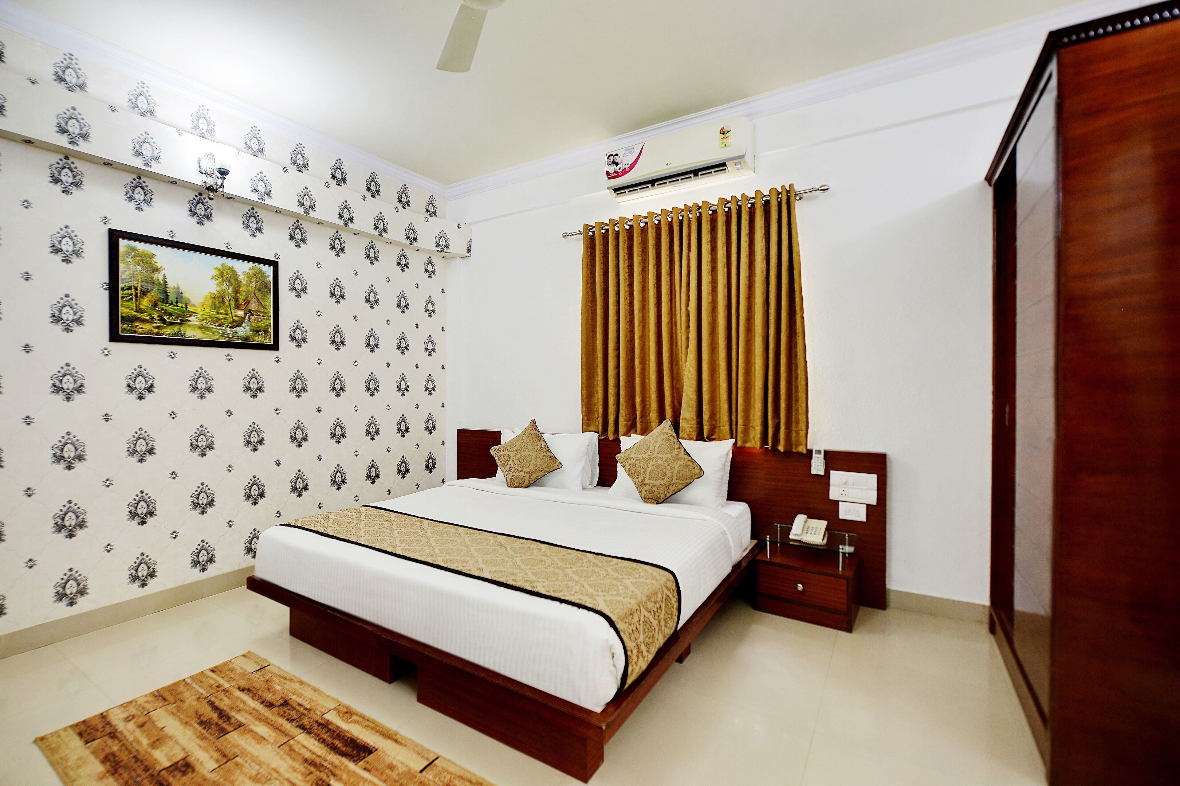 A bedroom with a bed, a nightstand, a wooden wardrobe, a wall-mounted air conditioner, and patterned wallpaper.