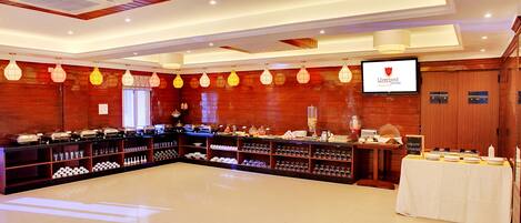 Una habitación amplia con una larga mesa buffet, paneles de madera y una pantalla de televisión mostrando 'Liverpool FC'.