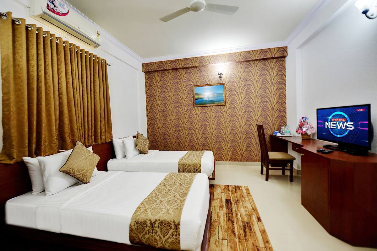A hotel room with two beds, a desk with a television, and a picture on the wall.