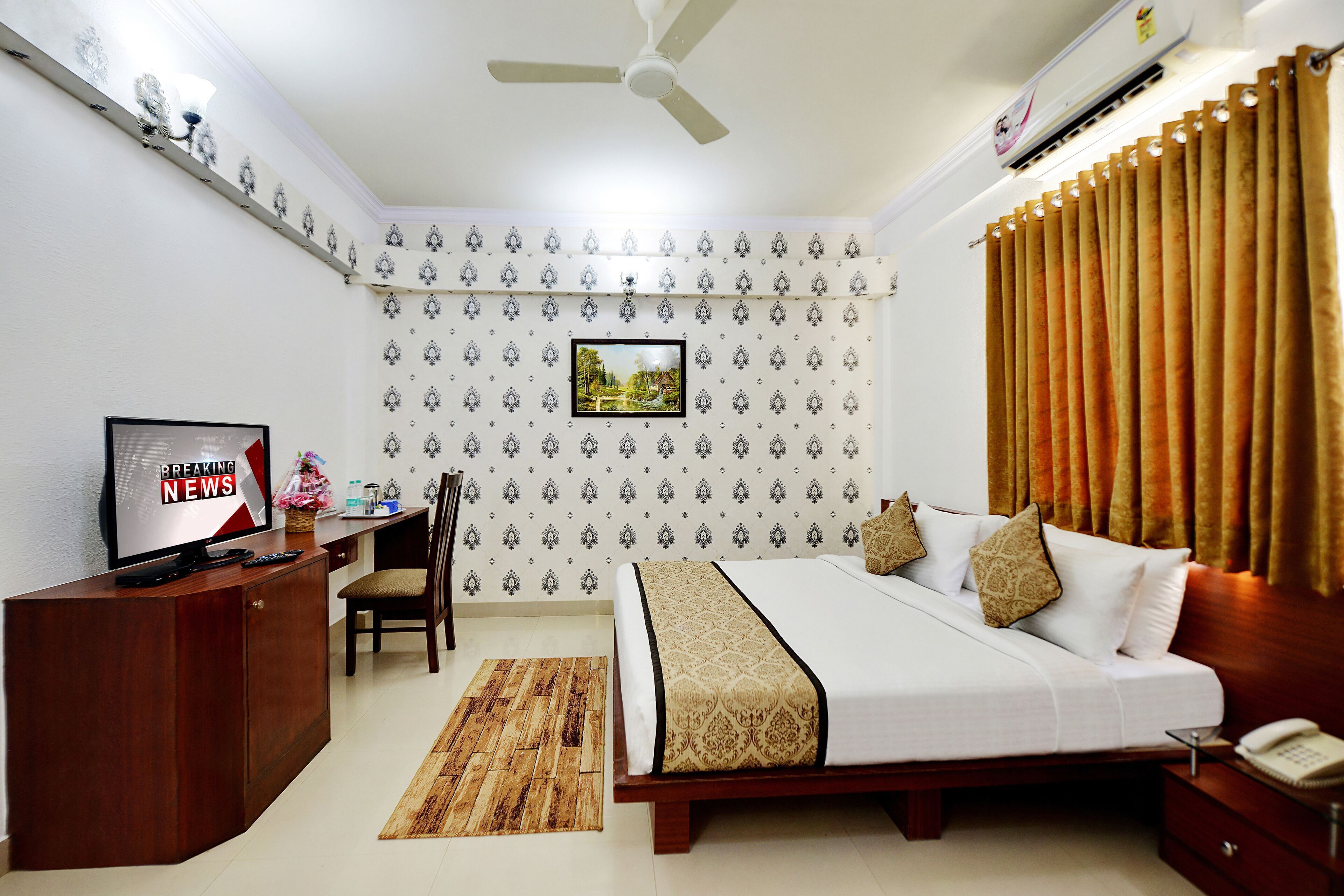 A hotel room with a bed, a desk, a chair, a television, and a window with curtains.
