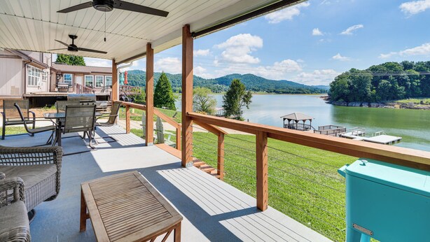 A covered deck with outdoor furniture, a view of a lake, and a distant mountain range. - Boat Dock + Covered Patio: Cherokee Lake Escape! (Mooresburg)