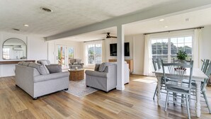 A spacious living area with a dining table, two sofas, and a TV mounted on the wall. - Boat Dock + Covered Patio: Cherokee Lake Escape! (Mooresburg)