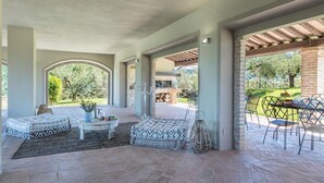 An outdoor patio area with seating, a fire pit, and a view of the surrounding landscape. - Le Residenze dei Potti 12 (Todi)