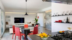 A modern kitchen with a dining area, a large flat-screen TV, and a variety of kitchenware on shelves. - Villa Pietro 10 in Nisporto (Rio)