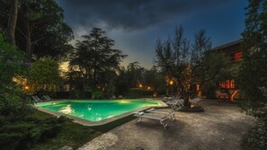A swimming pool with lounge chairs, surrounded by trees and a building with traditional architecture. - Villa Sylva 6 2 in Rome (Ciampino)