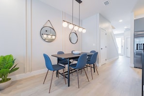 Un espace de salle à manger moderne avec une table ronde, des chaises bleues et des luminaires suspendus.