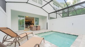 A swimming pool with lounge chairs and a covered patio area. - Your Orlando Retreat: Warm and Welcoming Townhome (Clermont)