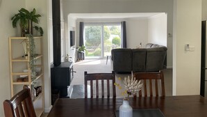 A dining area with a wooden table, chairs, a vase with dried flowers, and a view of a living room with a sofa and a ceiling fan. - Central Murtoa Home with Lake view, family friendly. (Murtoa)