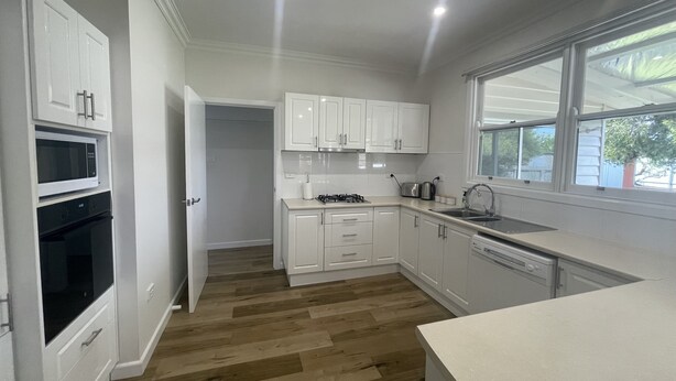 A modern kitchen with white cabinetry, a built-in microwave, and a dishwasher. - Central Murtoa Home with Lake view, family friendly. (Murtoa)