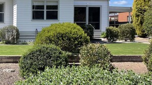 A single-story house with a green roof, a front porch, and a well-maintained lawn. - Central Murtoa Home with Lake view, family friendly. (Murtoa)