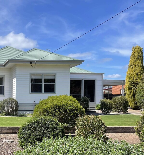A single-story house with a green roof, a front porch, and a well-maintained lawn. - Central Murtoa Home with Lake view, family friendly. (Murtoa)