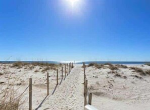 A sandy beach path with wooden posts, leading towards the ocean.