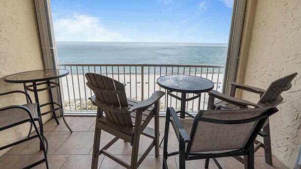 Un balcon avec vue sur l’océan, aménagé avec des chaises et des tables.