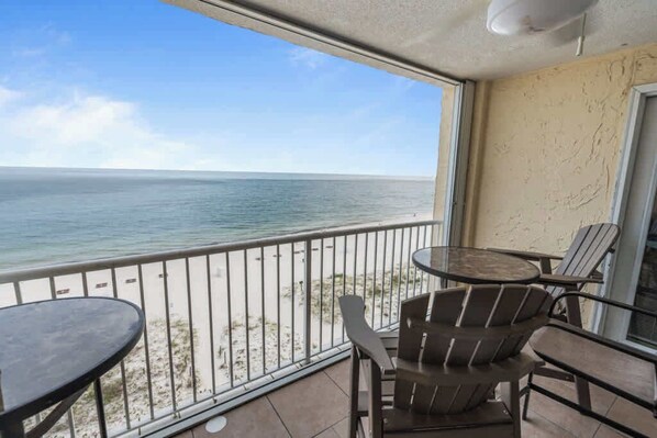 A balcony with a view of the ocean, a round table, and two chairs.