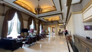 A spacious lobby with a grand chandelier, large windows with curtains, and elegant furniture. - GRAND EMPIRE PALACE HOTEL (Surabaya)