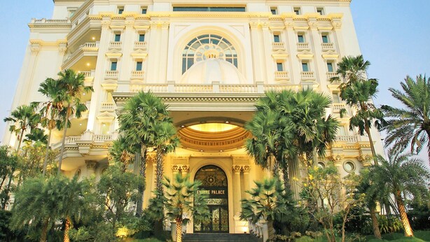 A grand building with a central dome, multiple balconies, and a well-maintained garden with palm trees. - GRAND EMPIRE PALACE HOTEL (Surabaya)