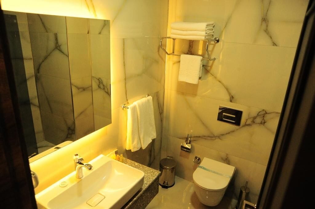 Un bagno con un lavandino in marmo, un water e uno specchio.