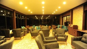 A spacious room with multiple seating areas, including sofas and chairs, arranged around a central table.