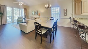 Amplia sala de estar con una mesa de comedor, sofás y una cocina con taburetes de bar.