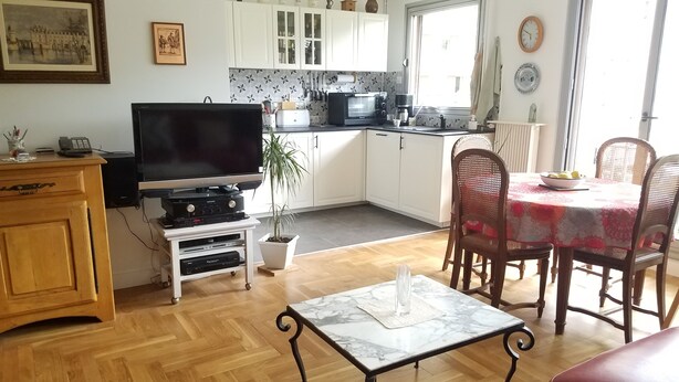 Eine moderne Küche mit weißen Schränken, einer schwarzen Mikrowelle und einem Essbereich mit einem Marmortisch und Korbstühlen.