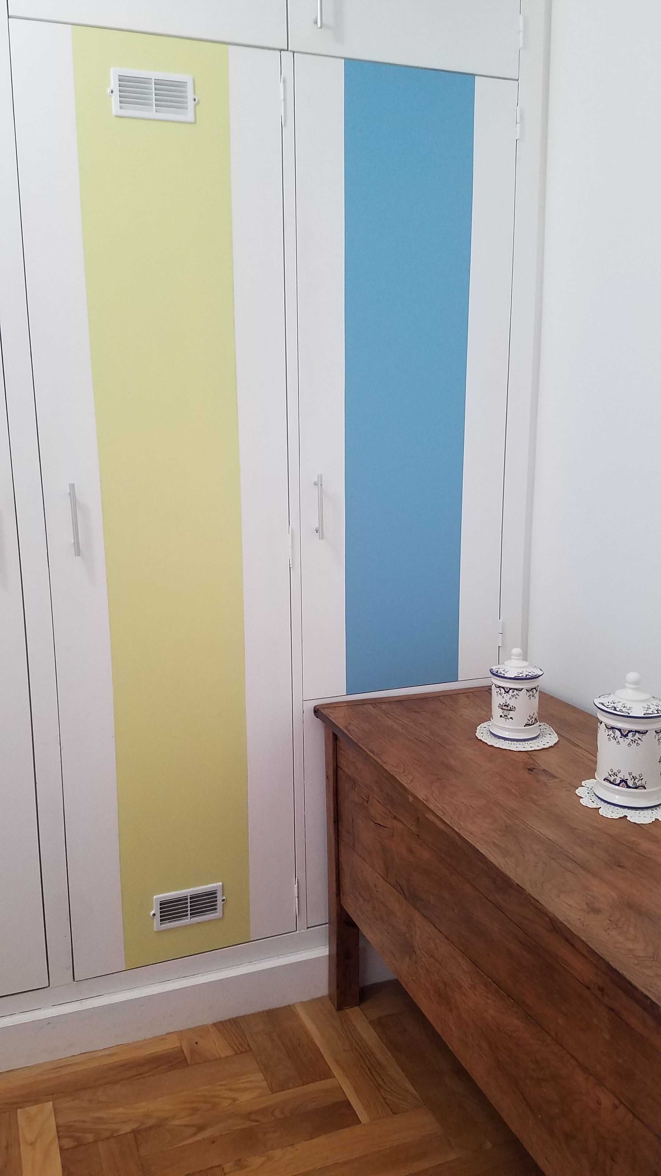 A wardrobe with three vertical sections in white, yellow, and blue.