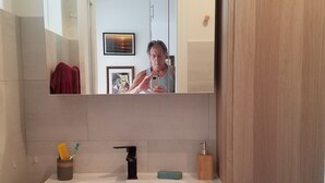Ein modernes Badezimmer mit einem großen Spiegel, einem Waschbecken und einem Holzschrank.